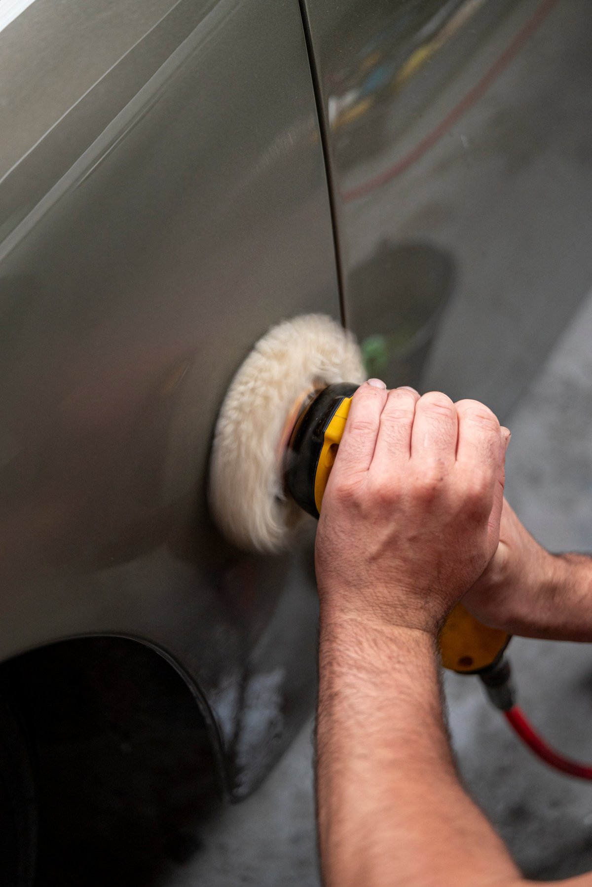 Rotary polisher polishing car paint to remove swirls and scratches during paint correction